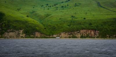 白色的汽车旅行道路中间的山和海
